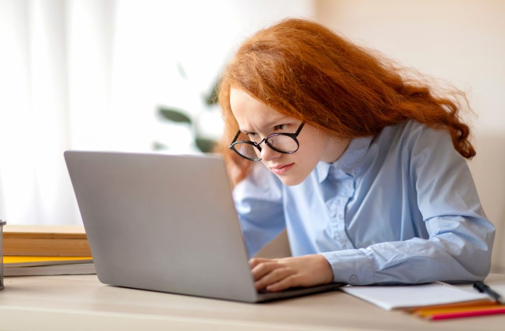 Young girl frustrated looking at laptop screen while she tries to finish her homework