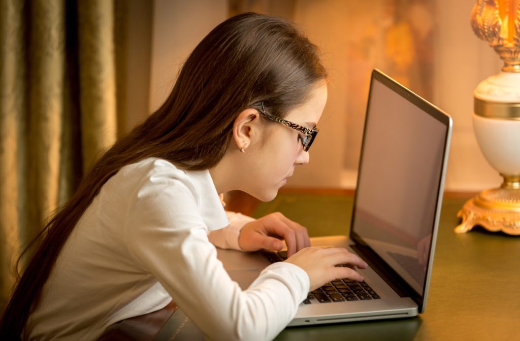 Young girl sitting close to laptop at her dinning room table.