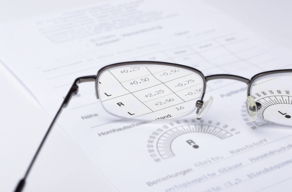 A black metal frame eyeglasses on top of an eyeglass prescription.