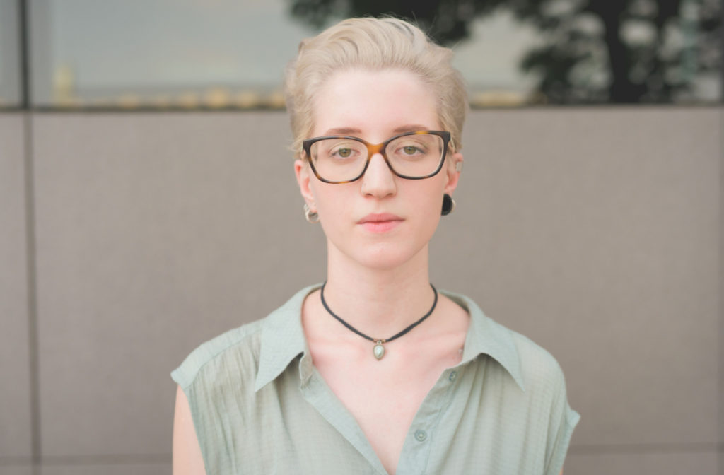 A short-haired young woman wearing a pair of glasses that complements the shape and the features of her face.