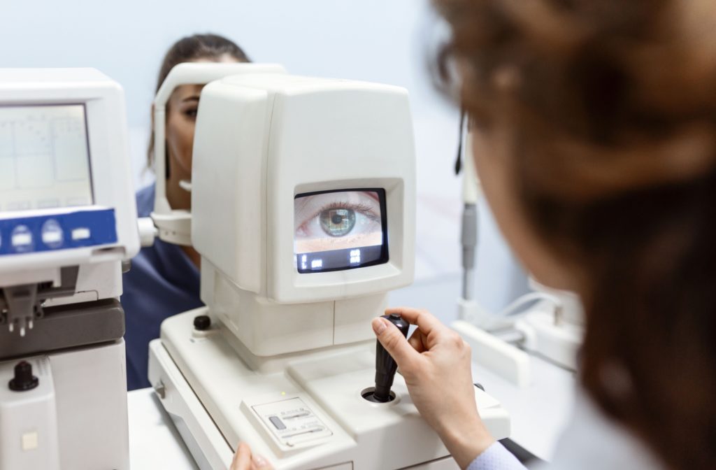 An eye doctor uses a digital optic apparatus to closely examine a patient's eye.