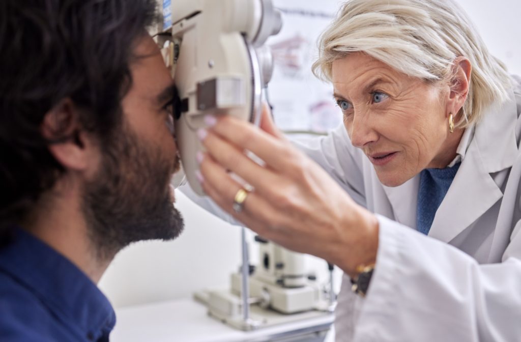 An eye doctor adjusts the lenses of a patient's acuity test equipment.