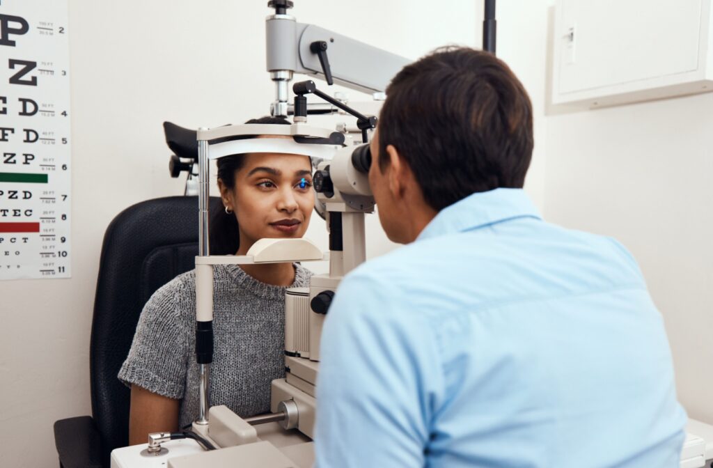 A patient is examined by an optometrist with a slit lamp, which shines a light into their eye, during a eye exam.
