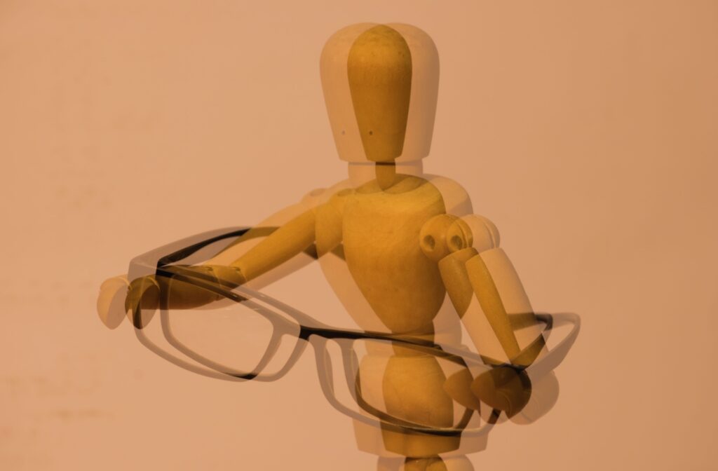 A double vision point of view of a figurine holding a pair of glasses.
